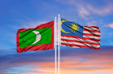 Malaysia and Maldives flag waving in the wind against white cloudy blue sky together. Diplomacy concept, international relations.