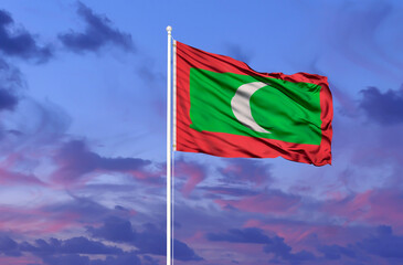 National flag of Maldives on a flagpole in front of blue sky