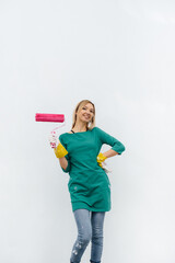A young girl poses with a pink roller before painting a white wall. Repair of the interior.