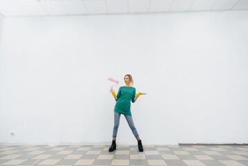 A young girl poses with a roller in front of a white wall. Repair of the interior.