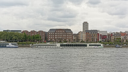 Naklejka premium Church and apartment buildings and cruise boats along river Rhine in Cologne