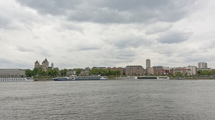 Fototapeta premium Church and apartment buildings and cruise boats along river Rhine in Cologne