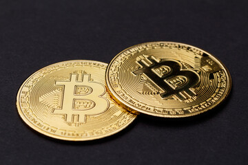 The concept of the bitcoin cryptocurrency financial market, trading. Two shiny gold bitcoin - macro. The bitcoin cryptocurrency is the coin of the future. The bitcoin logo on a dark background.