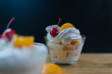 Cup of peaches and cream on wooden board with black background