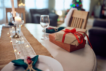 Christmas present on decorated dining table at home.