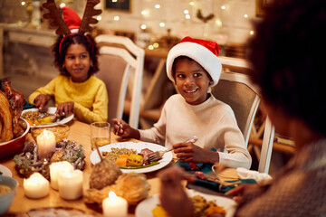 Happy African American boy enjoys in family meal at dining table for Christmas.