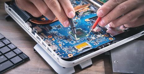 Technician hands checking motherboard with multimeter.