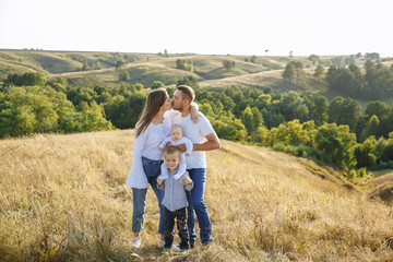 Fototapeta na wymiar family with small children posing in nature on a background of tall grass and canvas