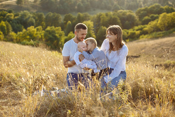 Naklejka na ściany i meble family with small children posing in nature on a background of tall grass and canvas