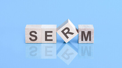 SERM word is made of wooden cubes lying on the blue table, concept