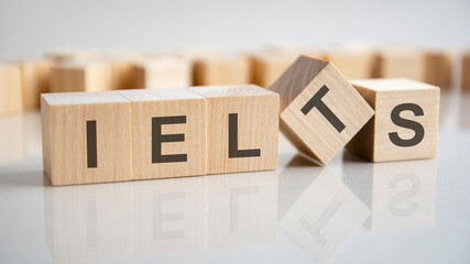 wooden cubes with the letters Ielts on the bright surface of a gray table, business concept.