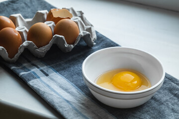 A plate with a broken egg near a chicken box on the kitchen table.