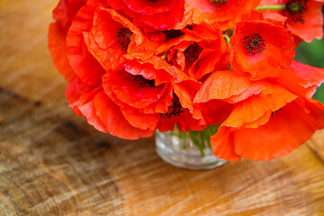 Beautiful bouquet of the red poppy flowers on ree stump outddors
