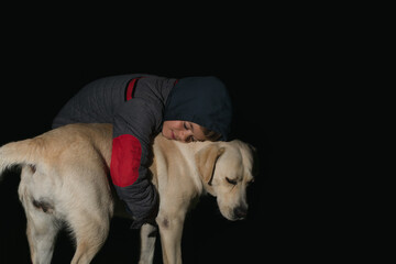 A little boy plays with a dog in the dark