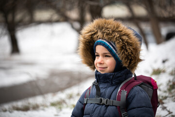 Portrait of smiling preschool boy in warm coat with hood in winter 