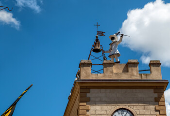 Fototapeta na wymiar Montepulciano, Tuscany, Italy. August 2020. Daytime footage in the historic center. A small tower is surmounted by the automaton of the pulcinella character who rings the bell