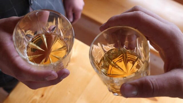 Two men drink cognac while making a toast at a celebration.