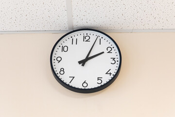 A large round indoor clock on the wall shows 14 o'clock.