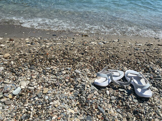 Flip-flops on the colored pebble beach. Summer and vacation concept