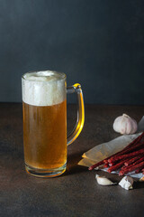 Glass of beer with foam and delicious thin smoked spicy sausages
