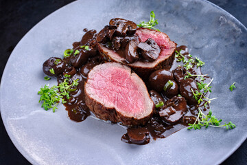 Modern style traditional fried dry aged angus beef filet medaillons natural with mushrooms in red...