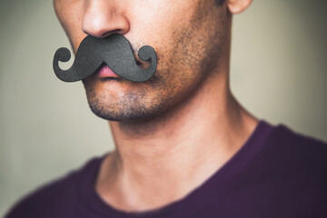 close up of a man's chin wearing a fake paper made mustache - Movember 