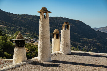 Typical chimneys on a rooftop in Capileira, with the Poqueira valley in the background, Las...