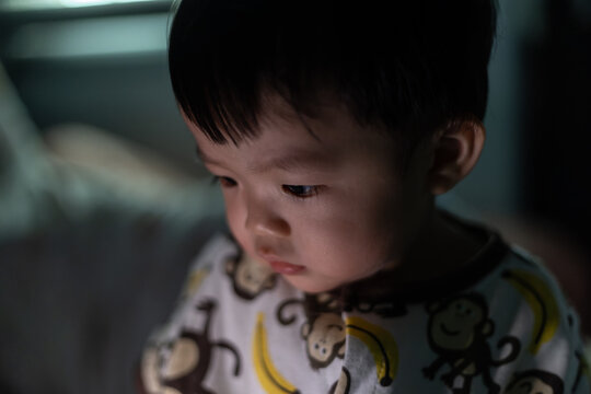 portrait image of 1 years old baby looking on smartphone on dark room