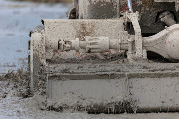 Close-up tractor cultivates and cuts furrows in the field. Tractor work in the black soil field in the village