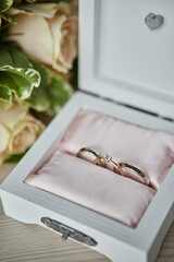 wedding rings lie on a beautiful box with flowers as bridal accessories