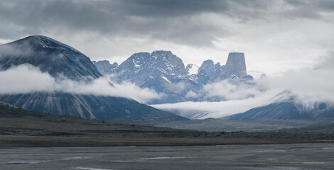 Iconic granite rock of Mt.Asgard towers above Turner glacier on a very cloudy and foggy day in...