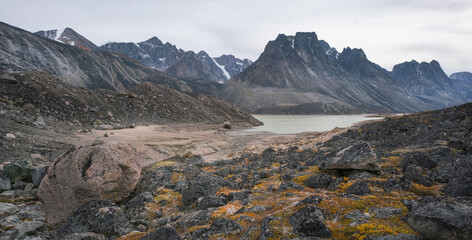 Dramatic mountain range in remote arctic valley of Akshayuk Pass, Baffin Island, Canada on a cloudy day of autumn. Landscape of remote wilderness in the far north