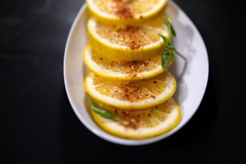 Plate of orange slices with chili powder on black surface