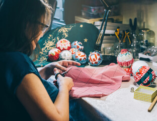 a craftswoman cuts a piece of cloth in her workshop to make christmas ornaments. concept of craftsmanship and local products.