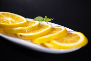 Plate of fresh orange slices above black background