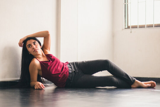 Latin woman posing in a red blouse. feminine identity: a confident young woman lying on the floor of her house. Colombian posing to the camera