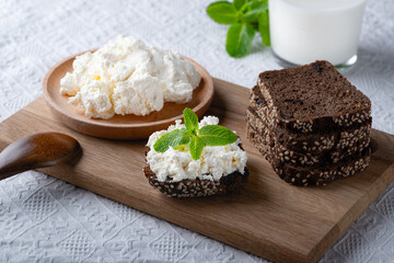 Rye bread on a wooden cutting board with curd cheese and milk