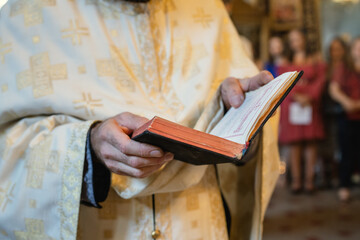 Close up on midsection of the orthodox priest holding the holy bible book during the wedding or...