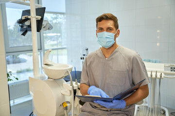 Friendly personnel of dental clinic posing with list of patients