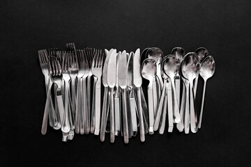 Simple style stainless steel cutlery viewed from above isolated on black background.