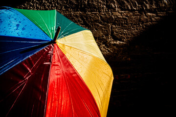 Open umbrella against the intense sun with bright colors and dark background.