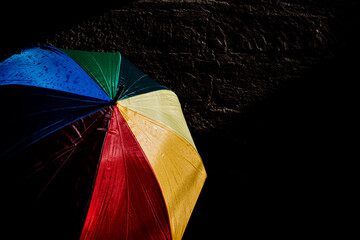 Open umbrella against the intense sun with bright colors and dark background.