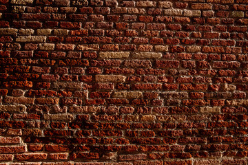 Texture of a red brick wall lit by the afternoon sun with copy space background.