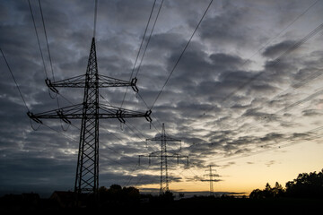 3 power poles with crossing power lines at sunset