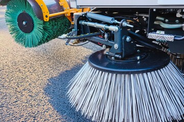 Combination of two sweeping brushes of municipal street sweeper machine close up. Year-round urban street cleaning concept. Modern street sweeping equipment.