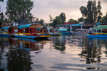 Fototapeta na wymiar Traditional colorful trajineras in Xochimilco lake under beautiful sky