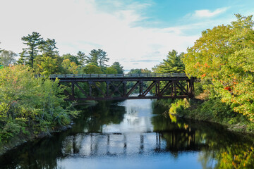 Fototapeta na wymiar Eastern Maine Railroad crossing bridge over river on an early fall evening