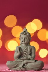 Fototapeta premium Buddha statue on red background with golden bokeh .Meditation and relaxation symbol.