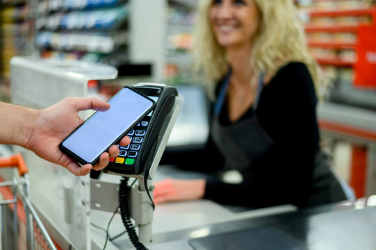 Mans hand making a contactless payment with his smartphone at a supermarket