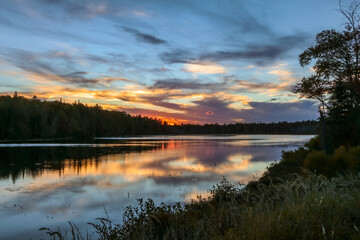 Fototapeta na wymiar Spectacle Pond near Moosehead Lake, Maine, at sunset with beautiful cloudscape colors